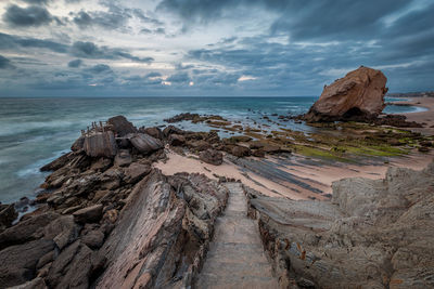 Rock formation on beach against sky