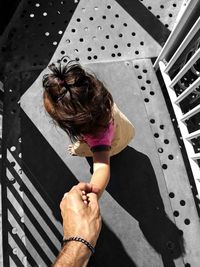 Cropped image of father holding daughter hand on footbridge