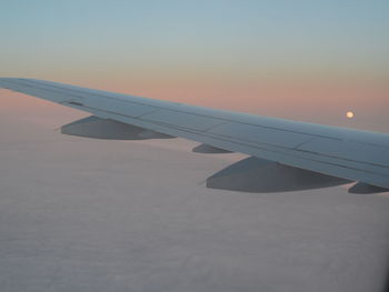 Close-up of airplane wing against sky during sunset