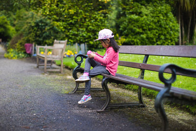 Young girl sitting on chair and watching her camera in summer garden