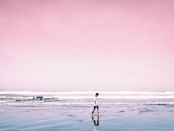 Rear view of shirtless man walking on beach