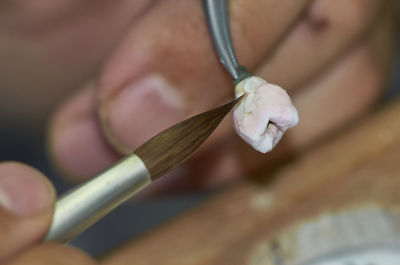 Close-up of hand using paintbrush on tooth