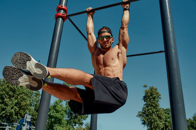 Low angle view of young man exercising against sky