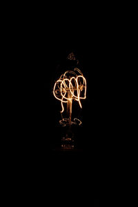 Low angle view of illuminated lighting equipment in darkroom against sky at night