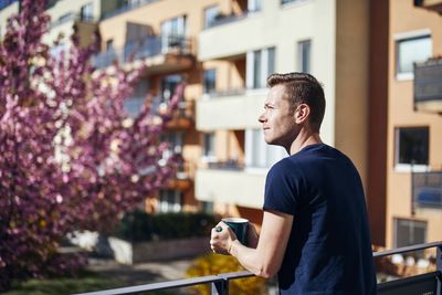 Man having coffee while standing at balcony