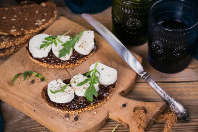 Bruschetta with fig jam, goat cheese and rucola on wooden plate. served with two glasses of red wine
