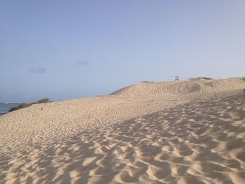 Sand dune on beach against clear sky