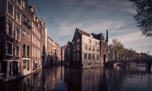 Canal amidst buildings in city against sky