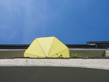 Low angle view of yellow umbrella on beach against blue sky