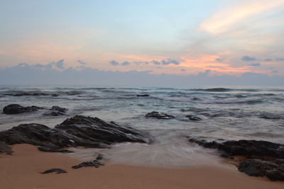 Scenic view of sea against cloudy sky during sunset