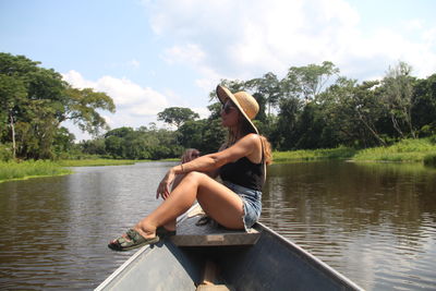 Rear view of woman kayaking in lake against sky