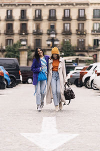 Happy female friends in colorful clothes strolling on street enjoying time together in city