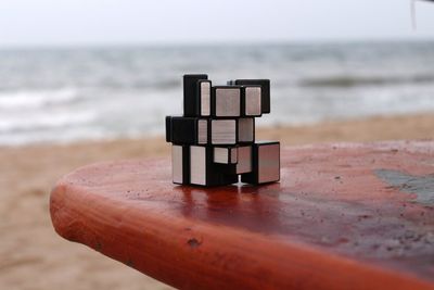 Close-up of chess board on beach against sky