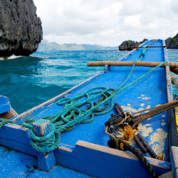 Fishing boats moored at sea shore against sky