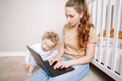 Mother with baby working on laptop from home. workplace of freelance business woman with kid 