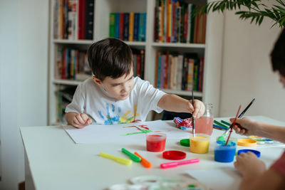 Boy doing painting while sitting at home