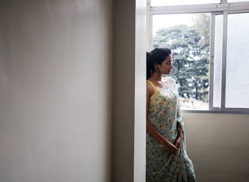 Side view of woman looking through window