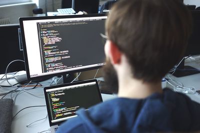 Rear view of man using computer at office