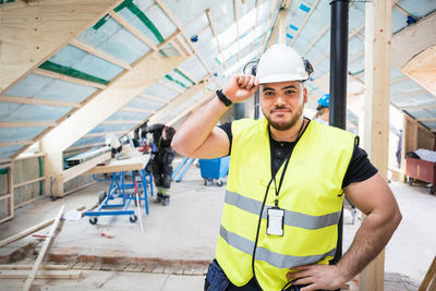 Portrait of confident manual worker wearing hardhat standing at construction site