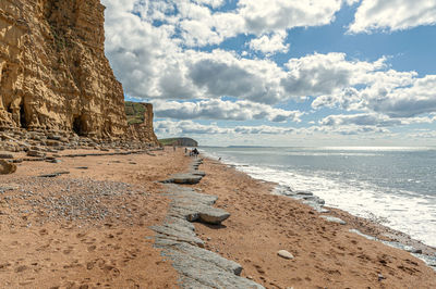 Rock formation on beach against sky