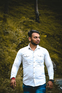 Portrait of young man standing against trees