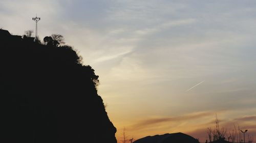 Low angle view of silhouette trees against cloudy sky