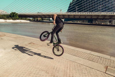 Man riding bmx cycle on footpath in city