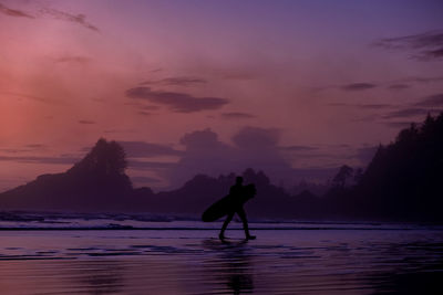 Silhouette man on beach against sky during sunset