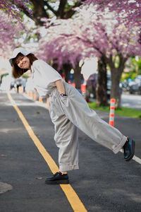 Full length of young woman on road against trees in city