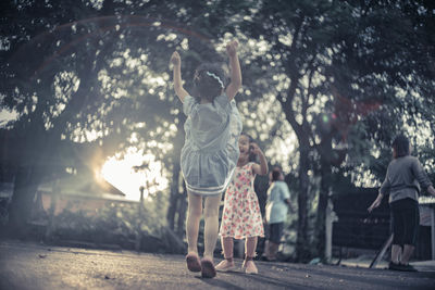 Siblings playing on road by trees