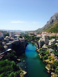 High angle view of river amidst buildings against blue sky