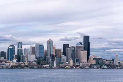 Sea by modern buildings against sky in city