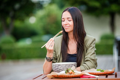 Young woman holding food while sitting on table