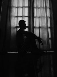 Side view of silhouette man sitting at home