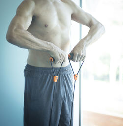 Shirtless man exercising by window