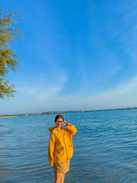 Rear view of woman standing at sea against sky