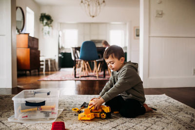 Toddler boy sitting inside putting together toy tractor