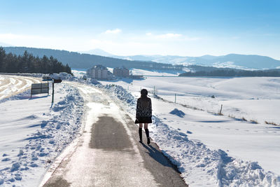 Rear view of woman walking on snow covered land