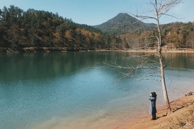 Man fishing in lake against sky