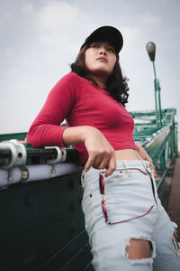 Portrait of woman standing by car against sky