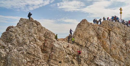 People on rock formation against sky