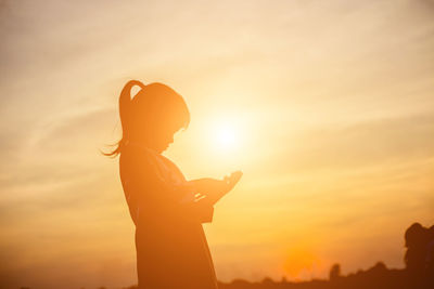 Silhouette man using smart phone against sky during sunset