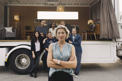 Portrait of confident businesswoman with team and portable office truck in background