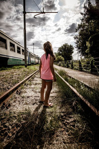 Rear view of woman standing on railroad track