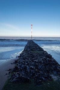 Coast of kent, scenic view of groyne with  warning pole and horizon over sea in the distance