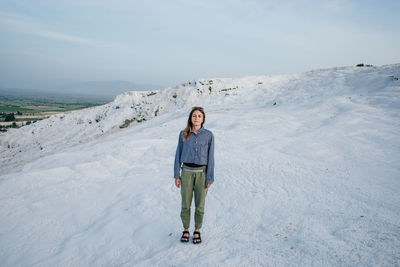 Portrait of woman standing in snow against sky