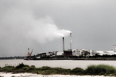 Industrial buildings against cloudy sky