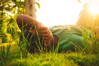 Close-up of man lying on grass in field during sunset