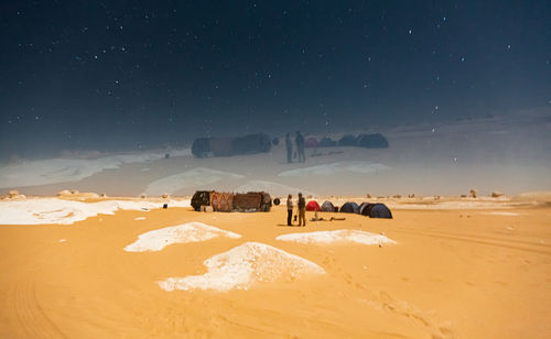 People on desert against sky at night