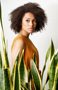 Portrait of young woman standing against plants